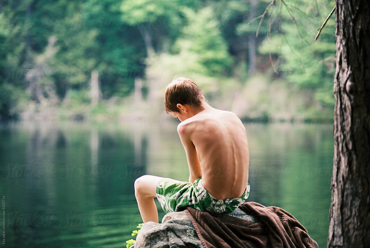 Stock Photo Of Teen Boy Sitting On Rock By A Lake By Stocksy