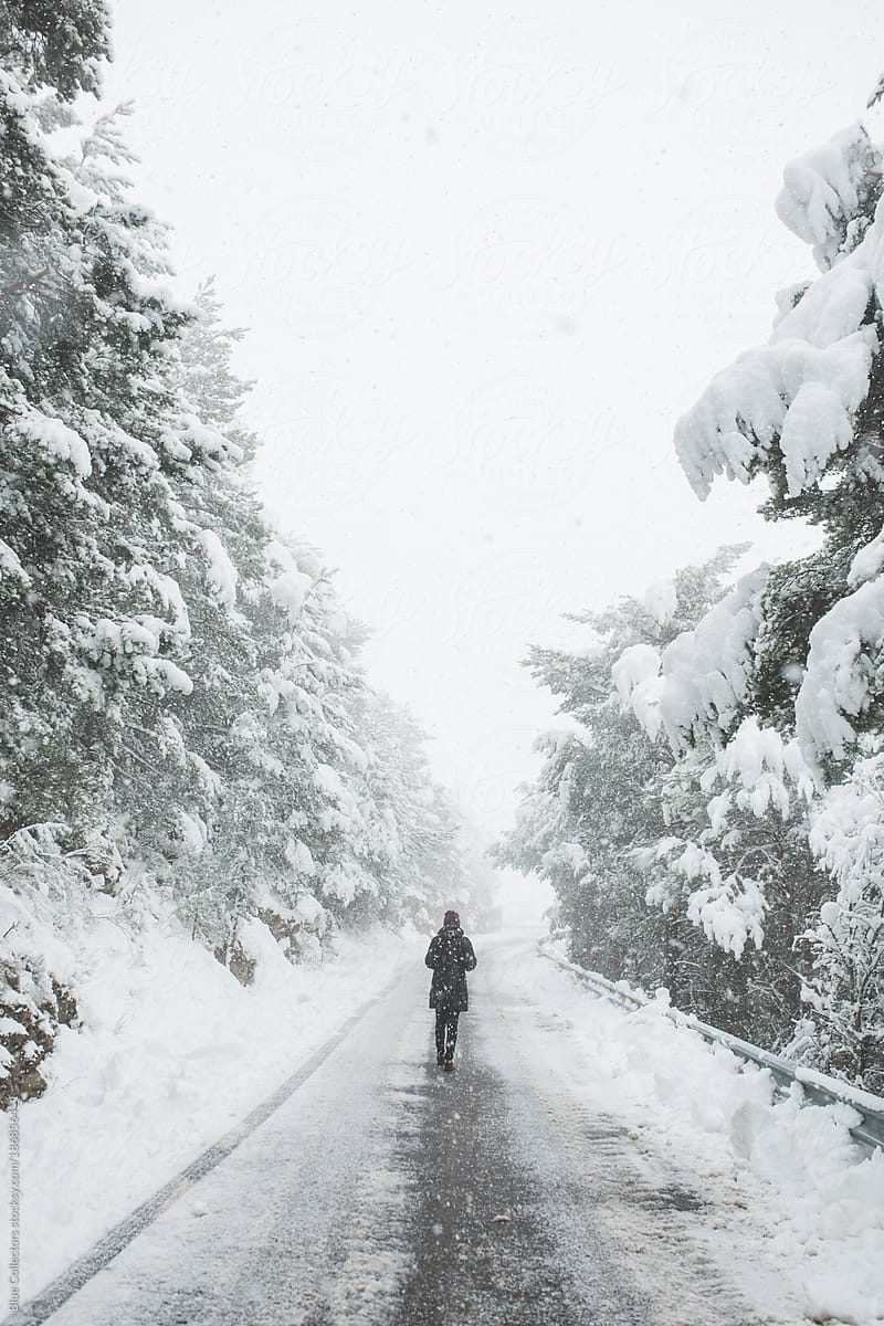 Woman Walking On The Snowy Mountain Road Del Colaborador De Stocksy