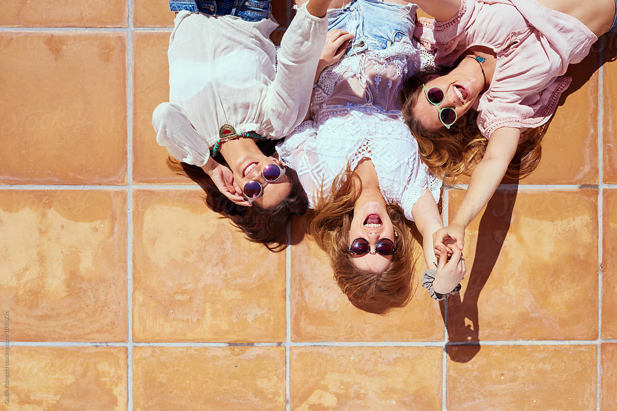 Three Cheerful Friends In Sunglasses Lying On Floor Del Colaborador