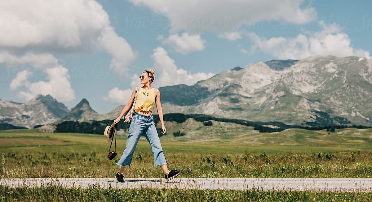 Woman Vacationer Walking On Mountain Road Del Colaborador De Stocksy