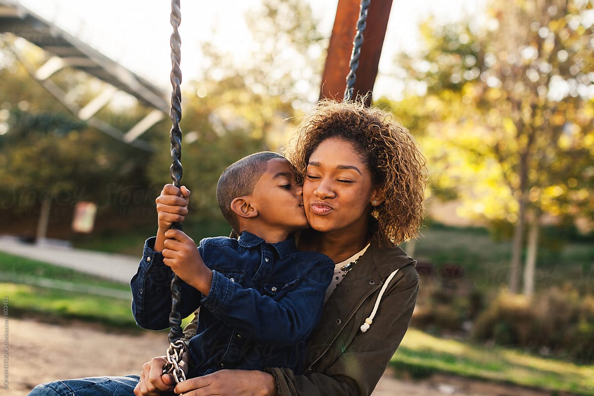Black Mother And Her Son Having Fun On Playground Swing By Stocksy