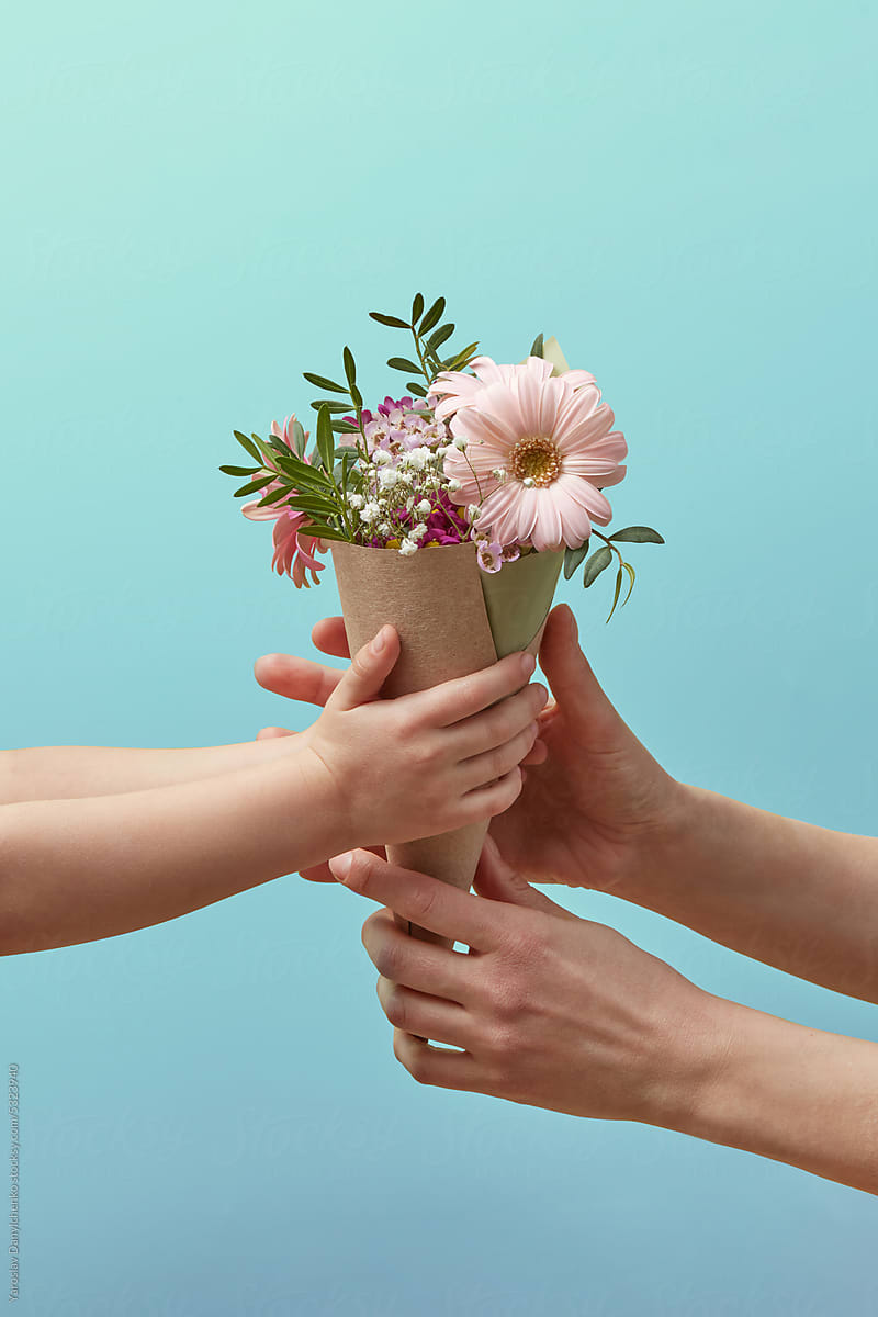 Hands of little daughter gifting flowers to mother.