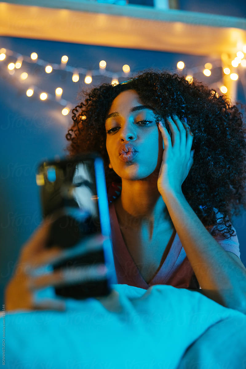 Black woman taking selfie in bedroom