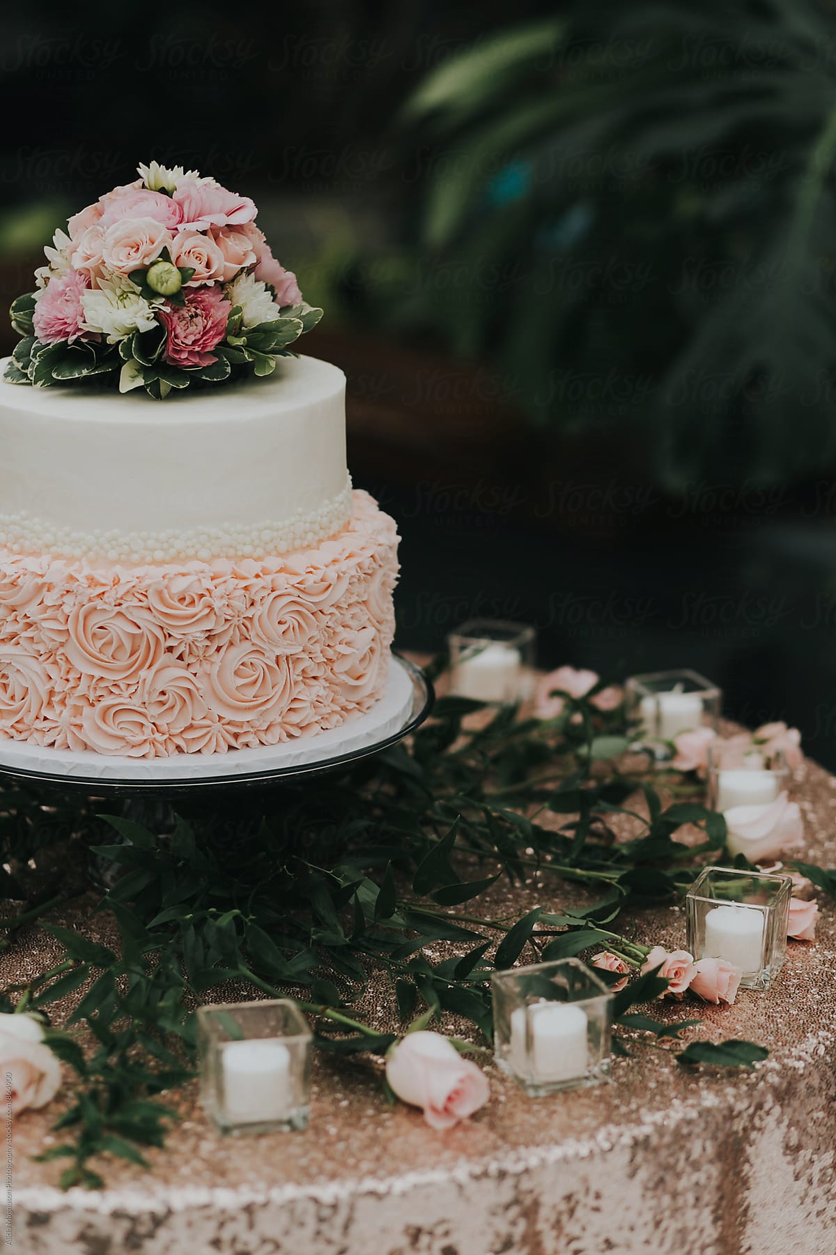 Detail of Blush Pink and White Wedding Cake on Candlelit Table
