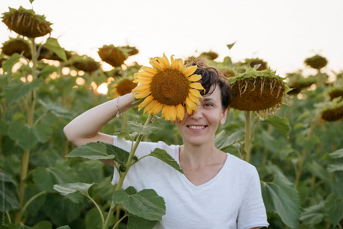 A woman is standing in a field with sunflowers and having fun