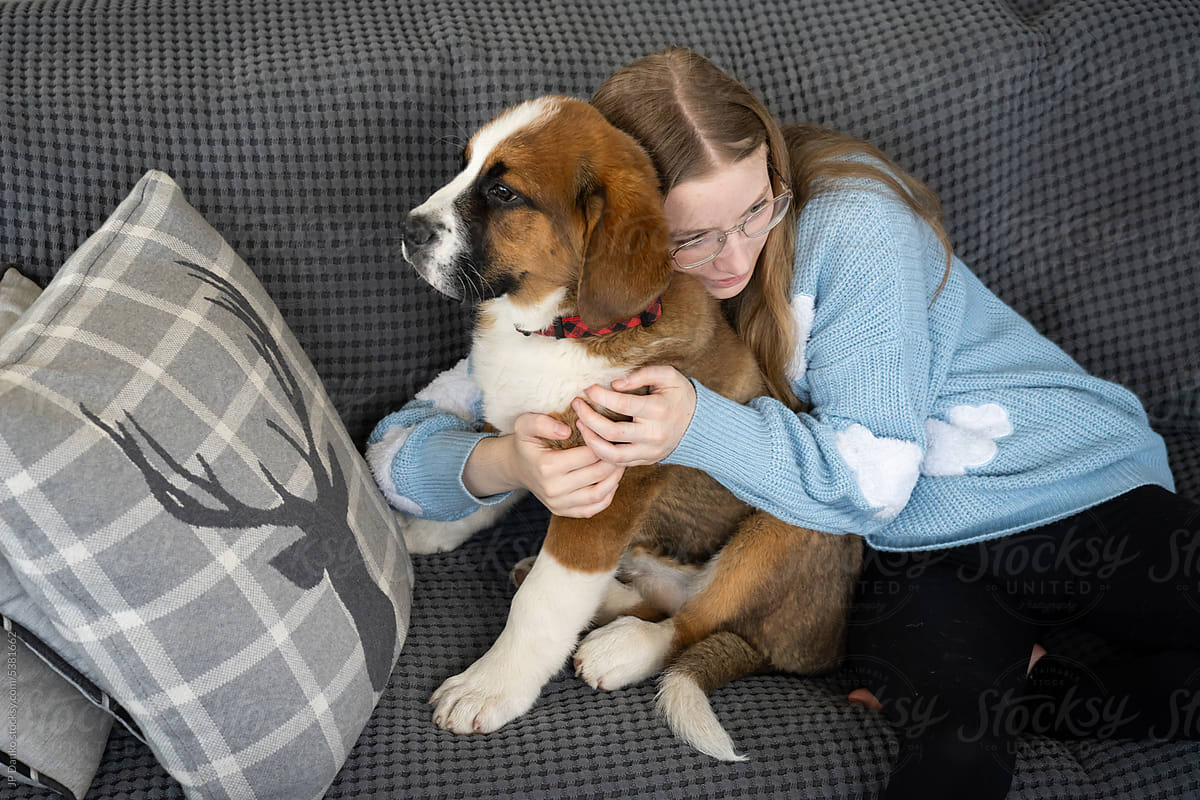 Teen Girl Hugging Large Mixed Breed Puppy Dog