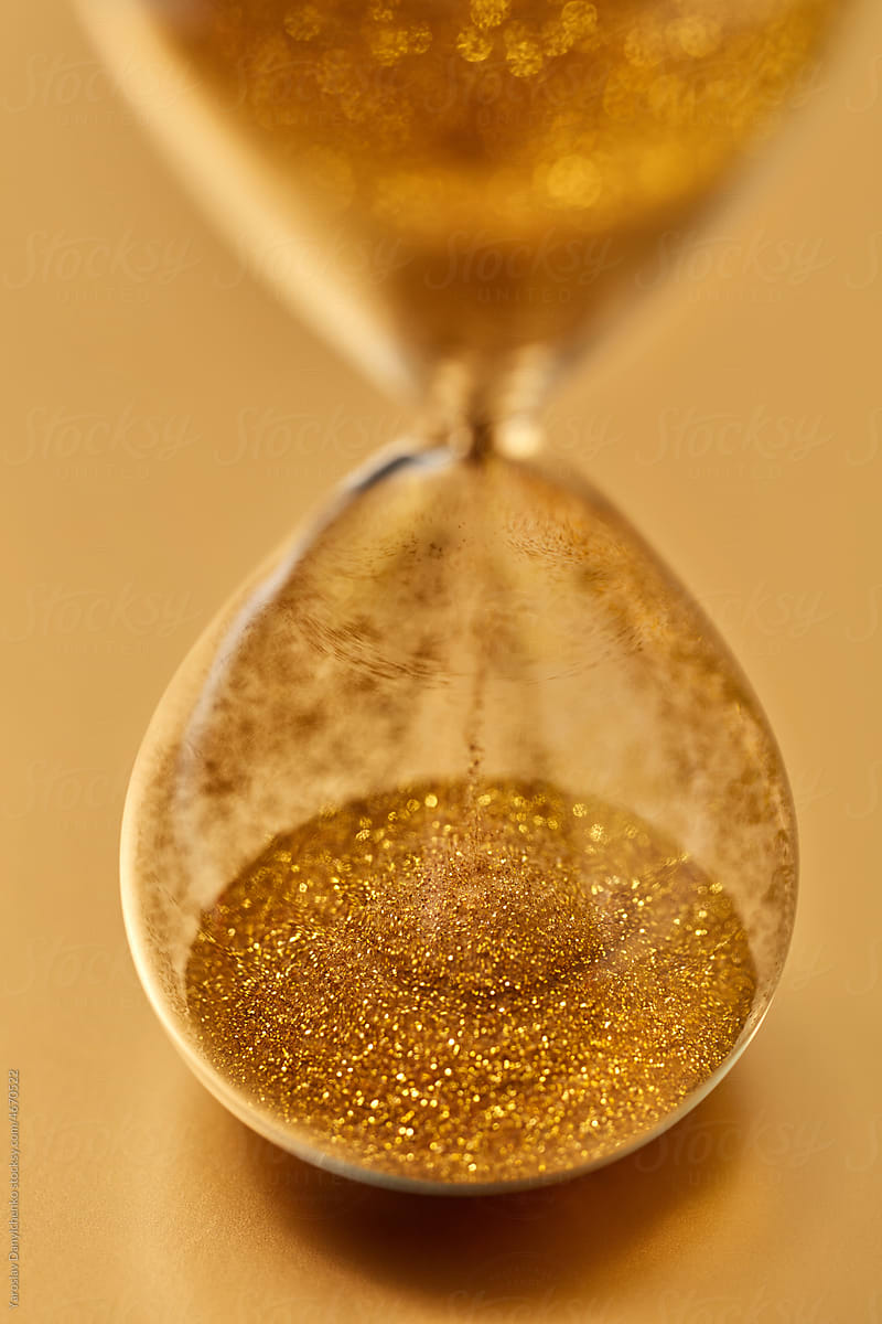 Close up of vintage hourglass with falling golden sand