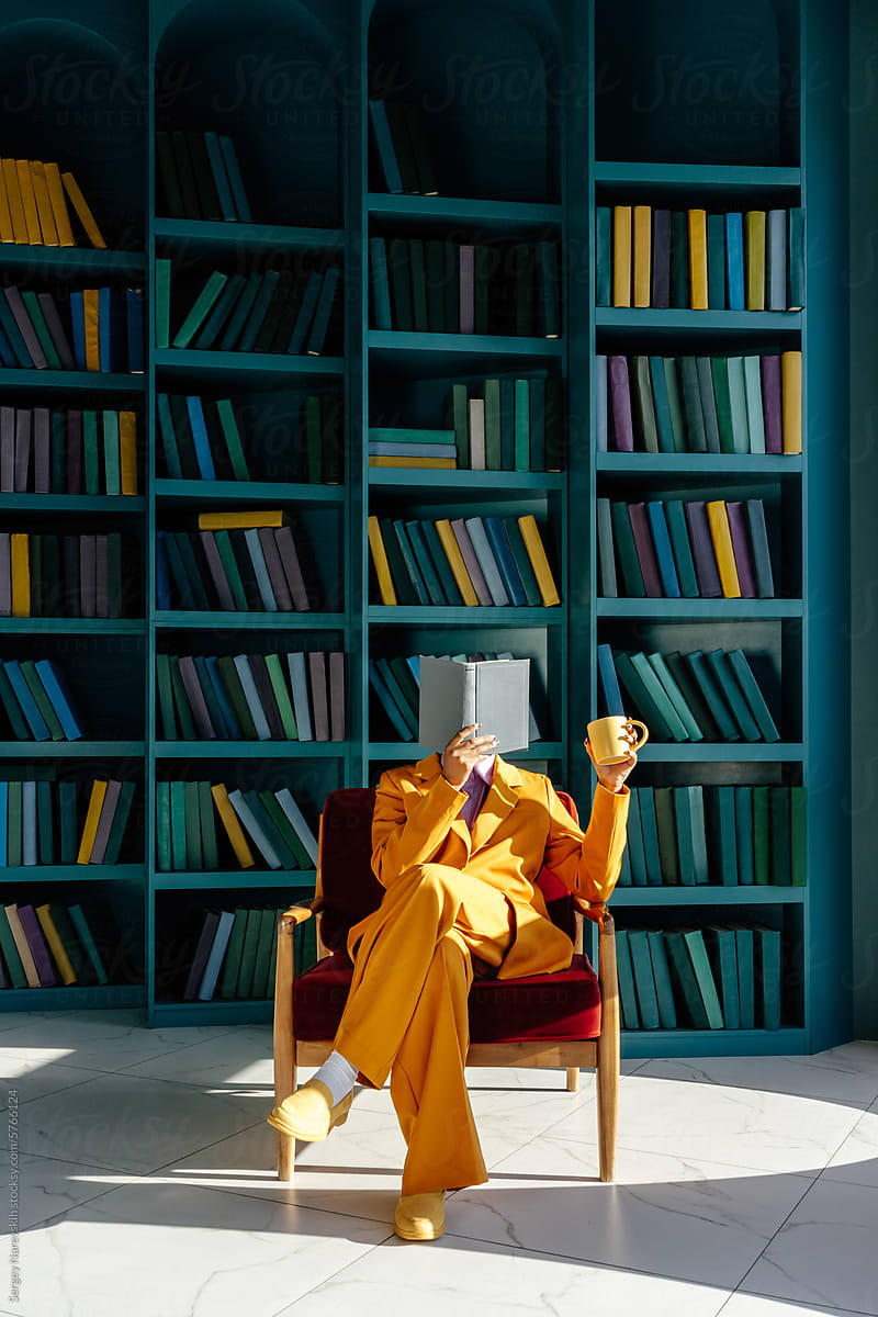 Woman in suit with mug and opened book in armchair