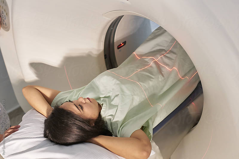 Female patient lying still with arms behind her head before ct scan examination