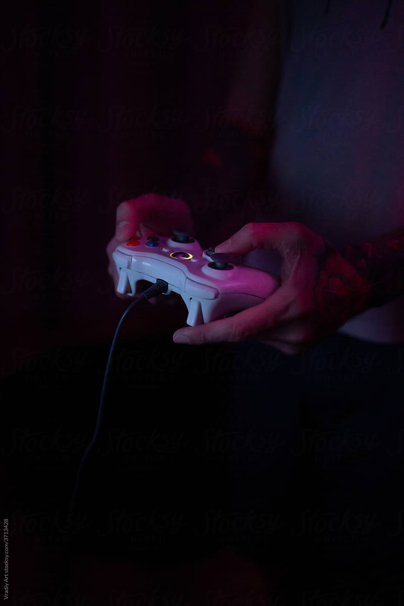 Anonymous person holding gamepad in neon light