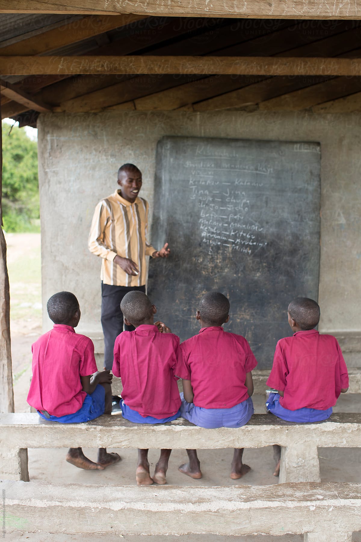 Teacher with schoolboys in outdoor classroom. Kenya.