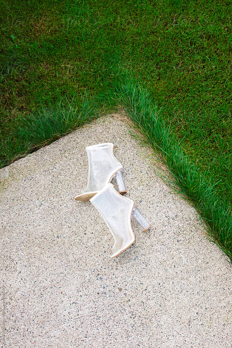 Transparent plastic classic heels laying on a  green grass in a garden