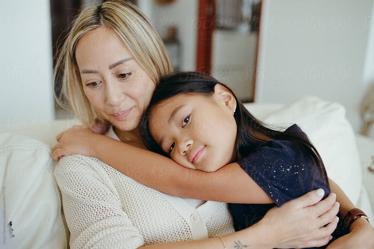 A girl with mother cuddling on the sofa