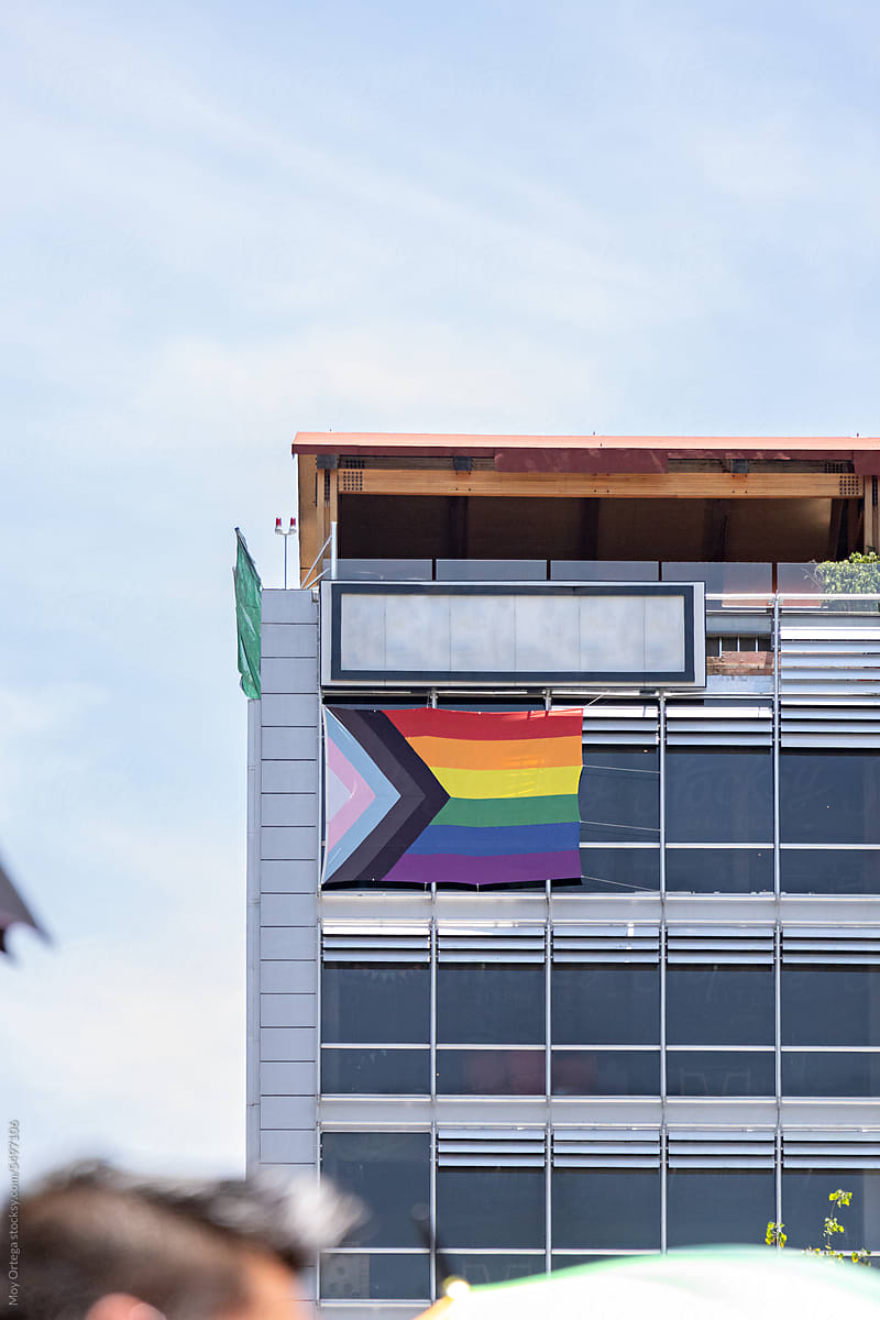 A LGBT+ Flag Hanging In The Upper Corner Of An Office Building
