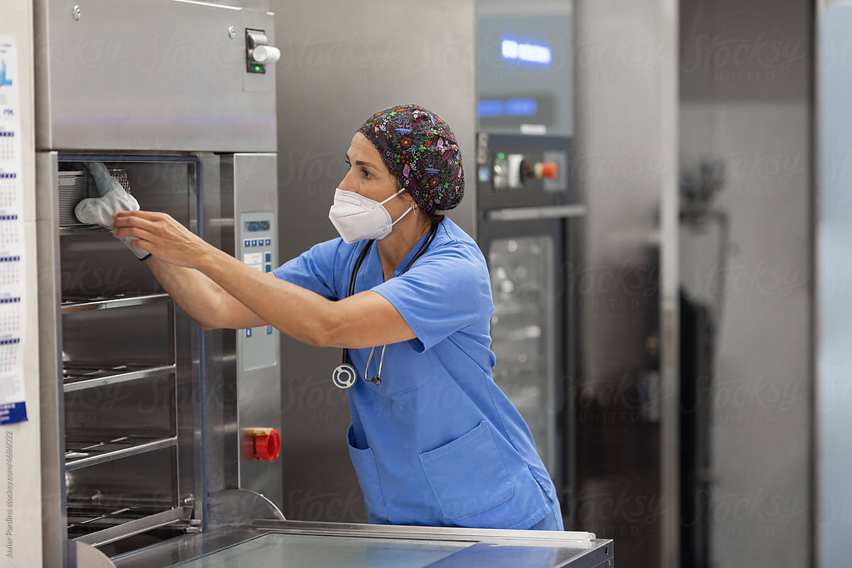 nurse with facemask, working with  Washer Disinfector Machine.
