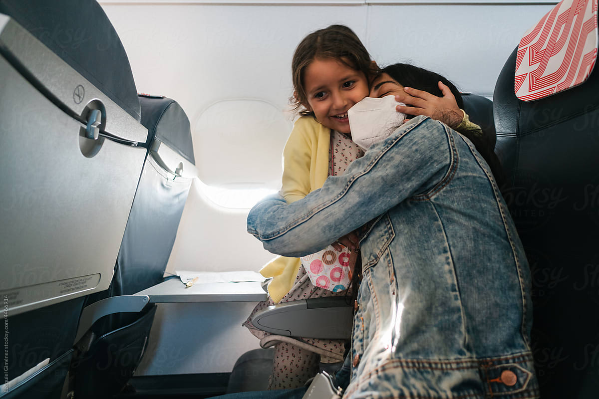 Happy woman and girl embracing in airplane