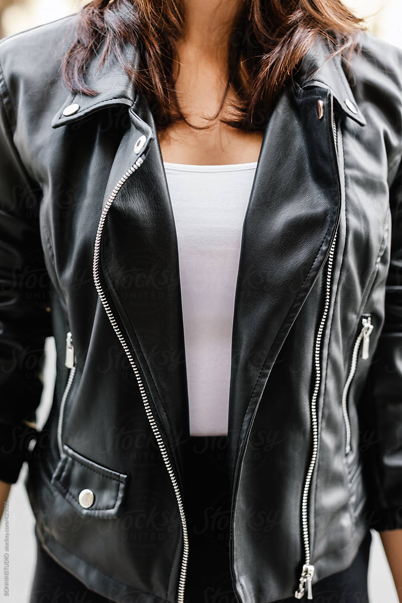 Closeup of woman wearing leather jacket and long black skirt.