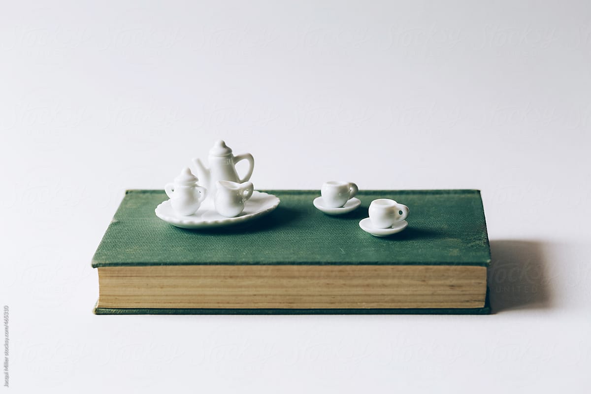 Tiny white tea set on vintage book