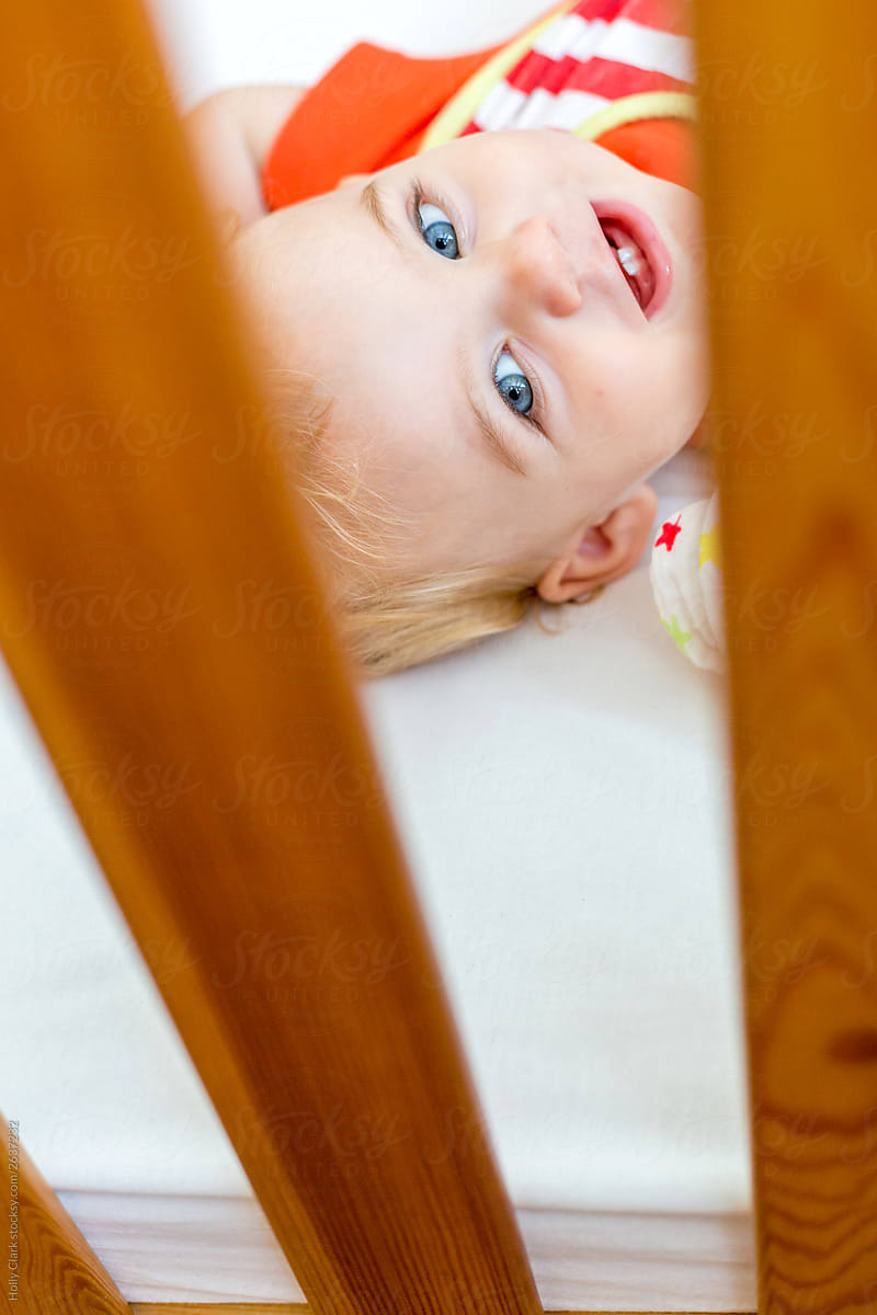 Face of smiling child with blue eyes in crib
