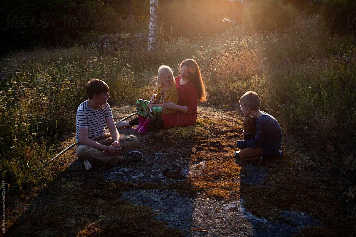 A mother enjoys a moment with her children as the sun sets in rural Finland.