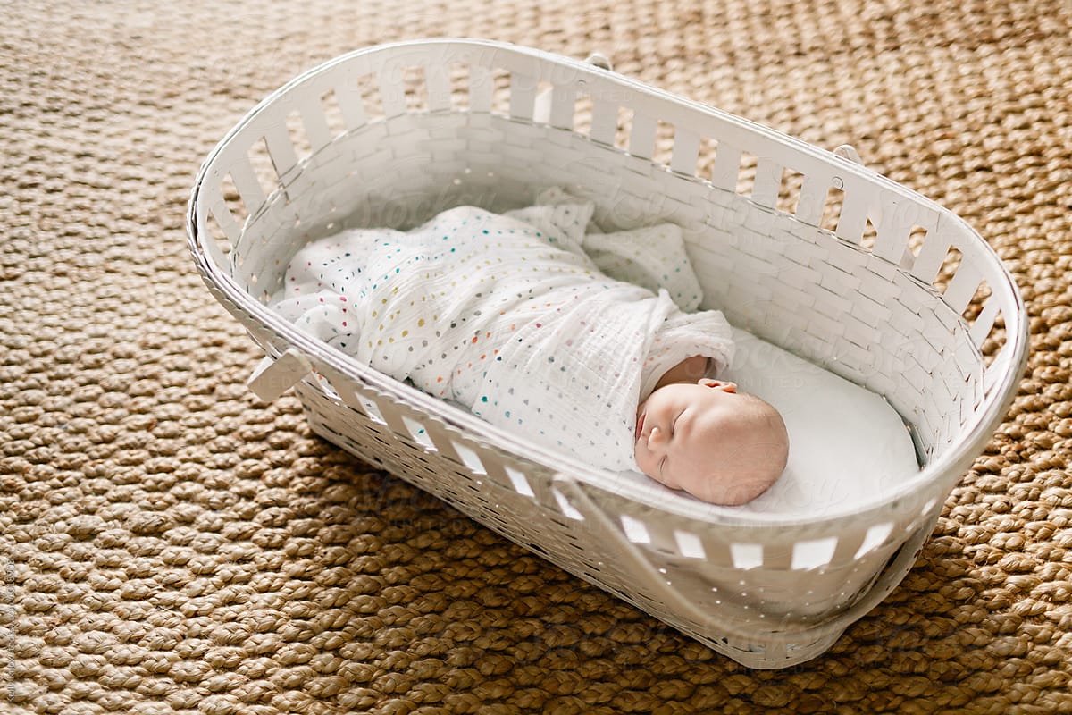 newborn sleeping in a vintage baby basket