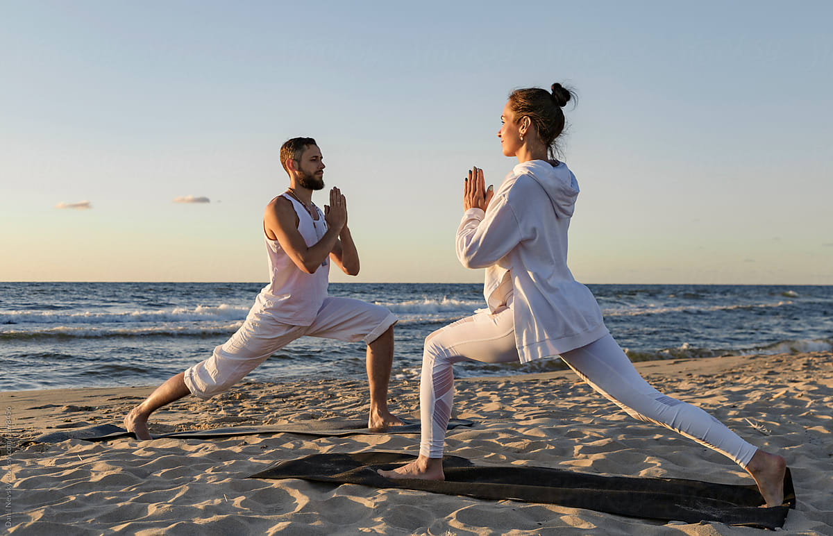 Couple doing yoga in morning on beach