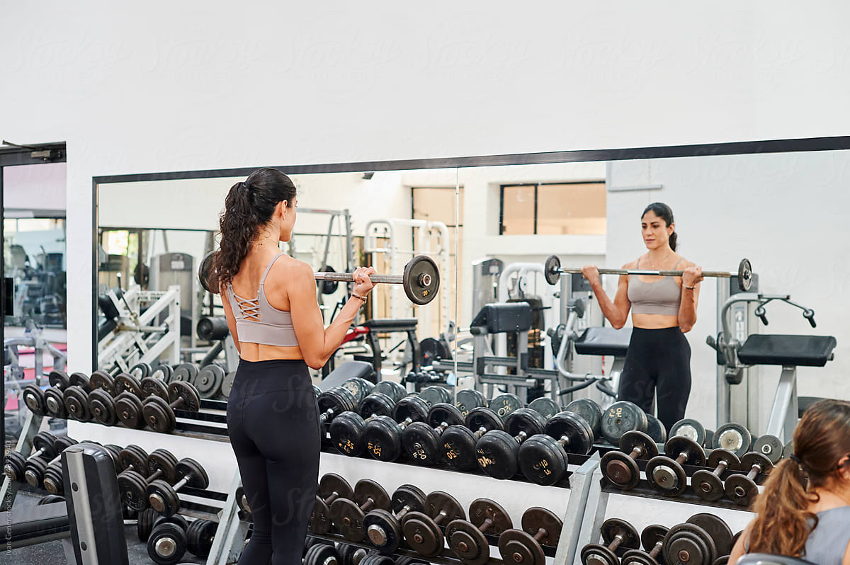 Woman lifting weights in a gym mirror