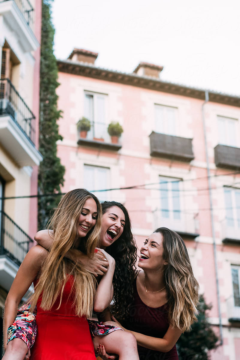 three women waking and laughing in a picturesque street in a summer evening