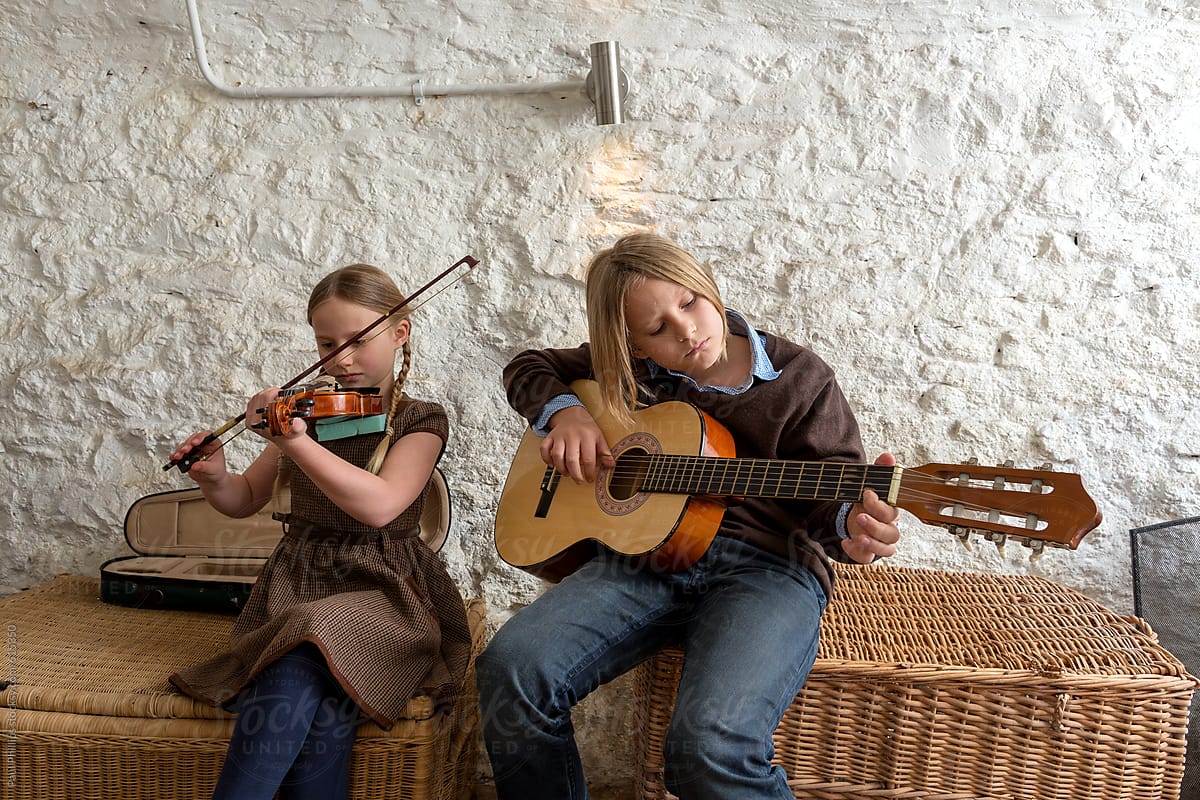 Children playing a guitar and violin in the cellar of an old house