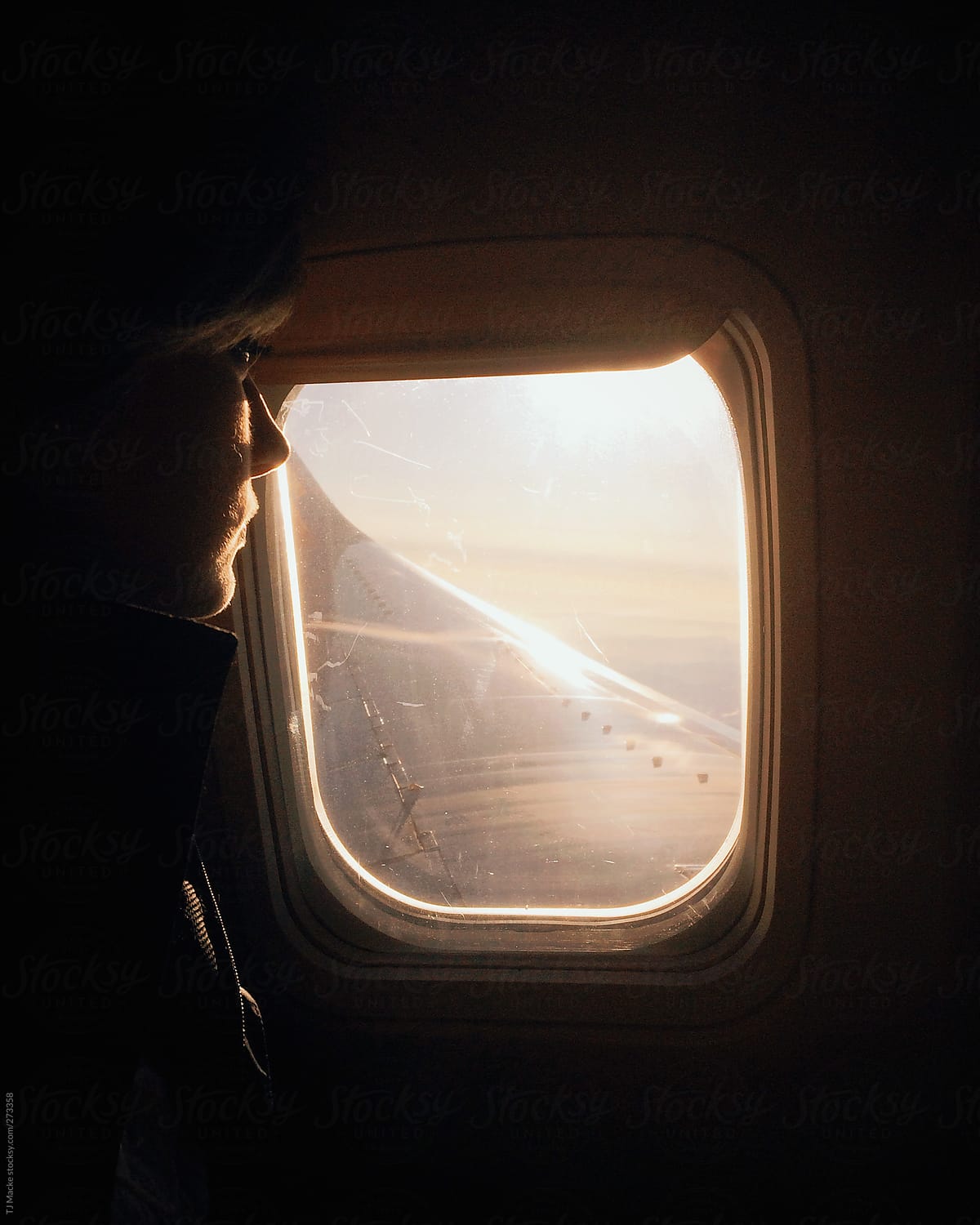 woman looking out the window of an airplane in the early morning