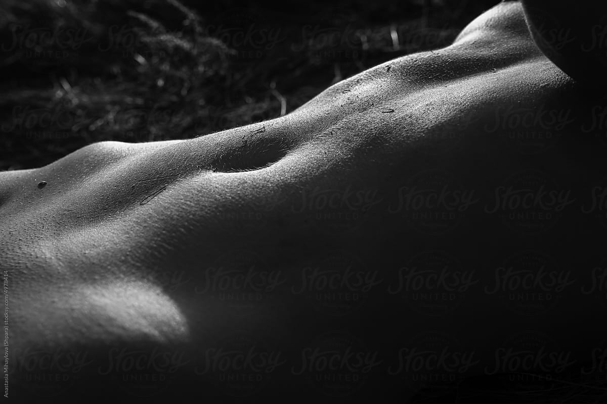 Black and white close up photo of female belly texture in sunlight