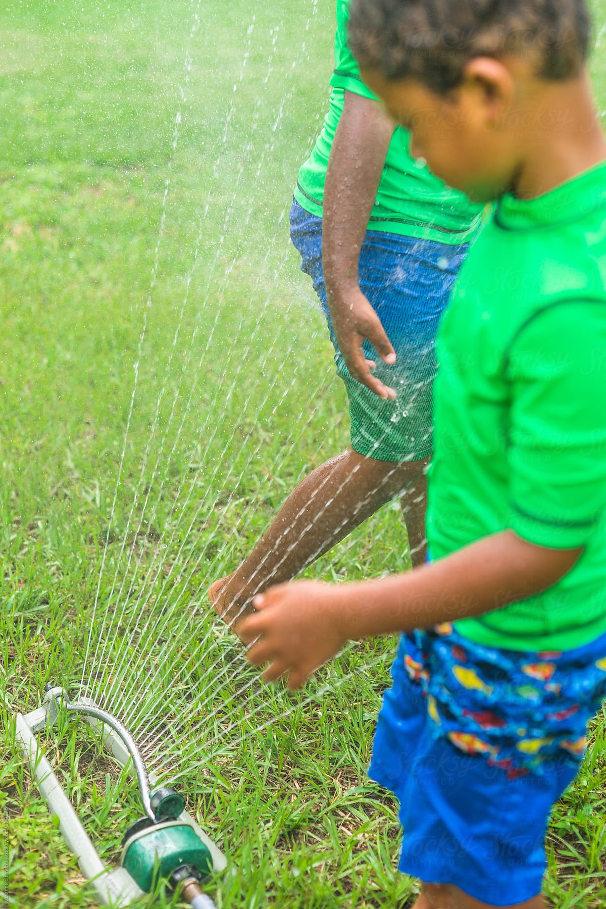 Boys Play in the Lawn Sprinkler