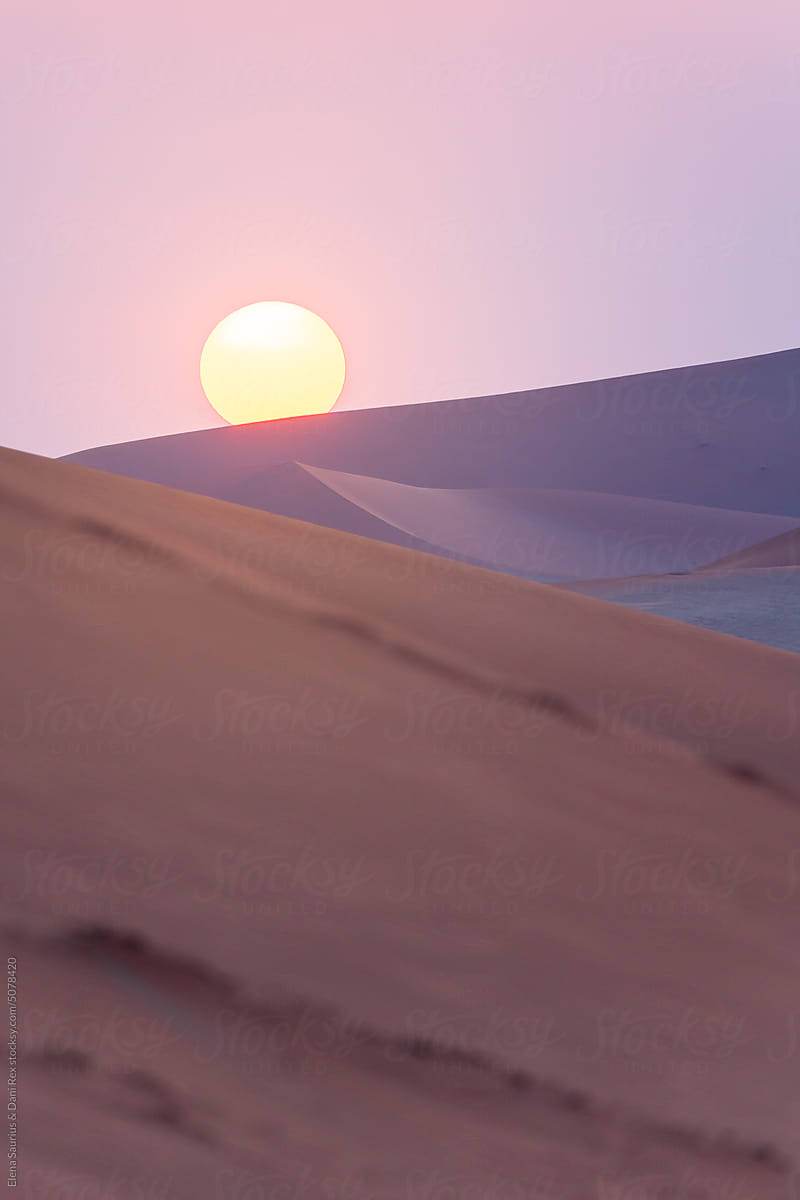 Sand dunes in front of the sun at sunset in Namibia, Africa.