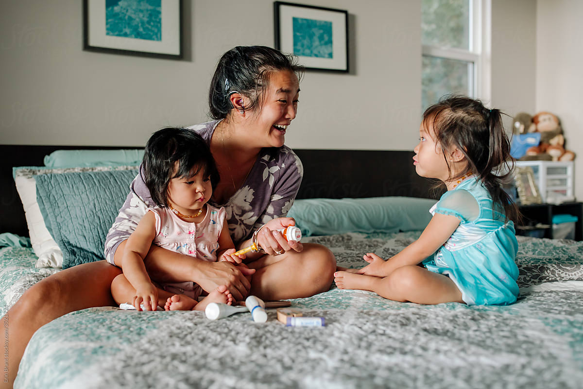 Smiling deaf mom on bed with daughters