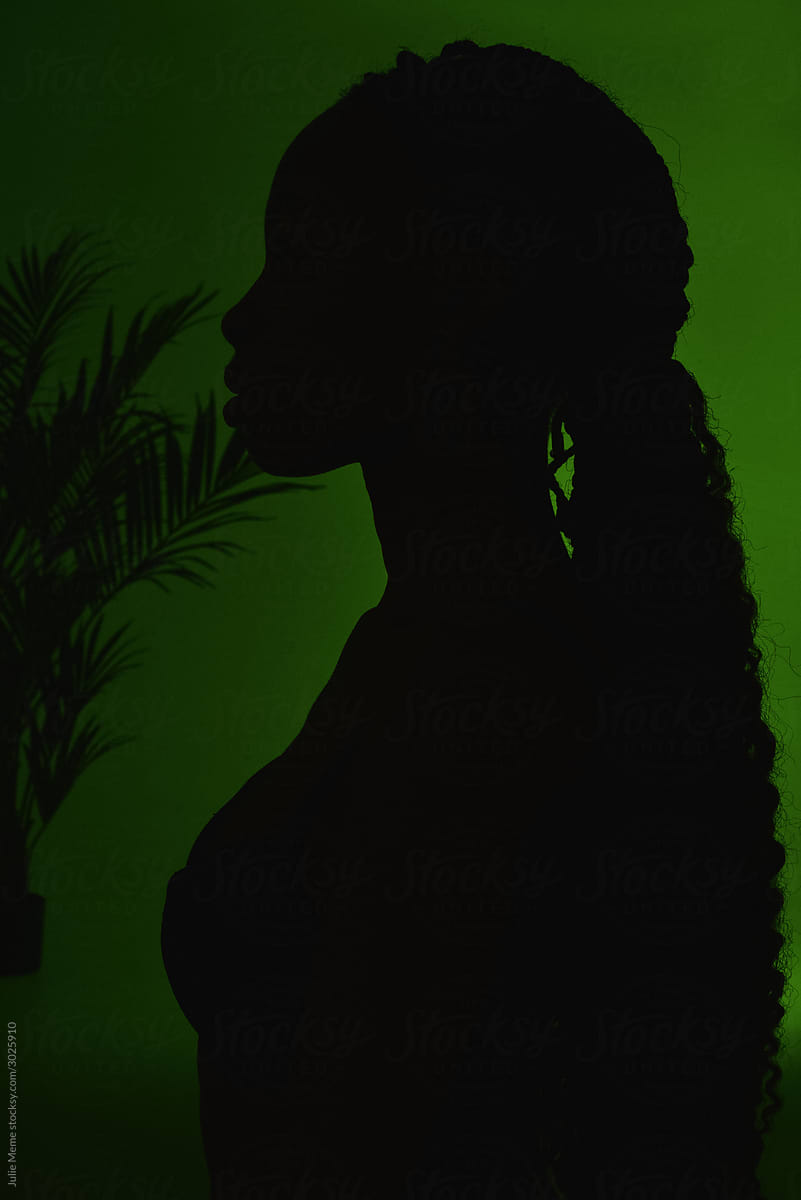 Silhouette of a black girl on the green background with palm leaves