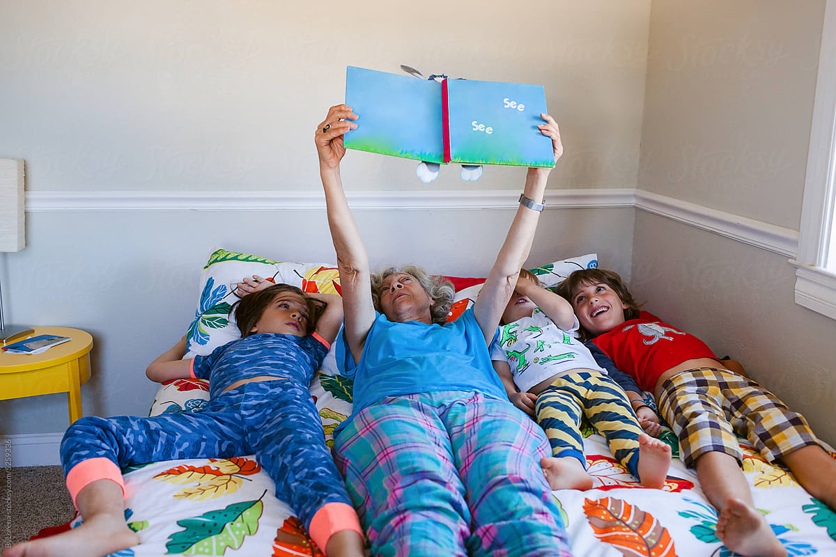 Grandmother and grandchildren reading on the bed