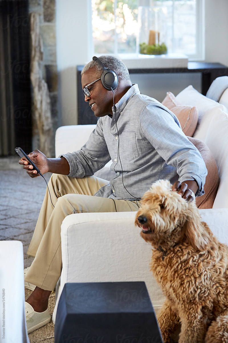 African American Senior man listening to music with dog