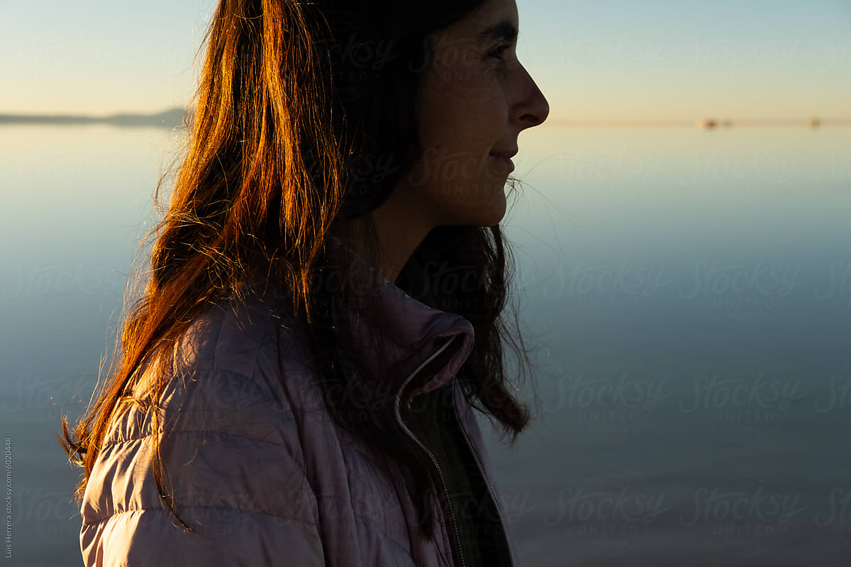 backlit profile of woman with long hair at sunset