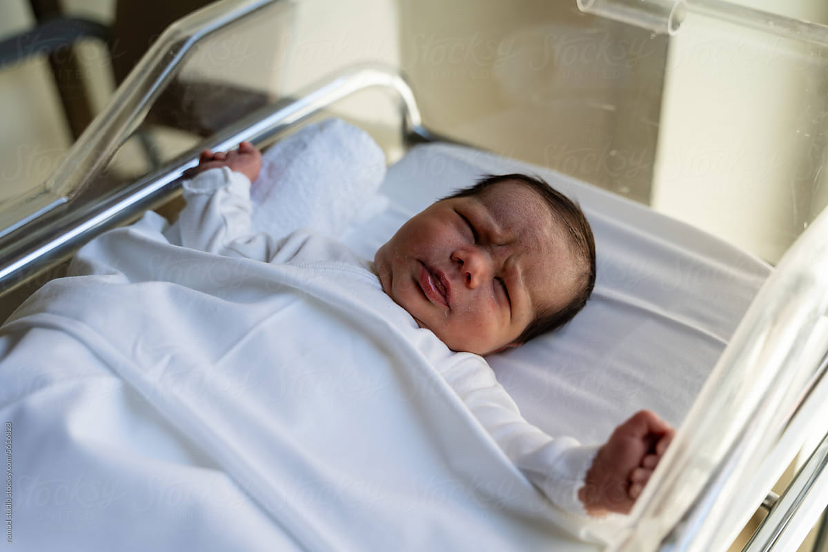 Newborn baby in hospital crib.