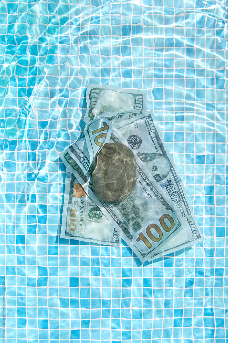 Dollar bills gliding across the swimming pool water.