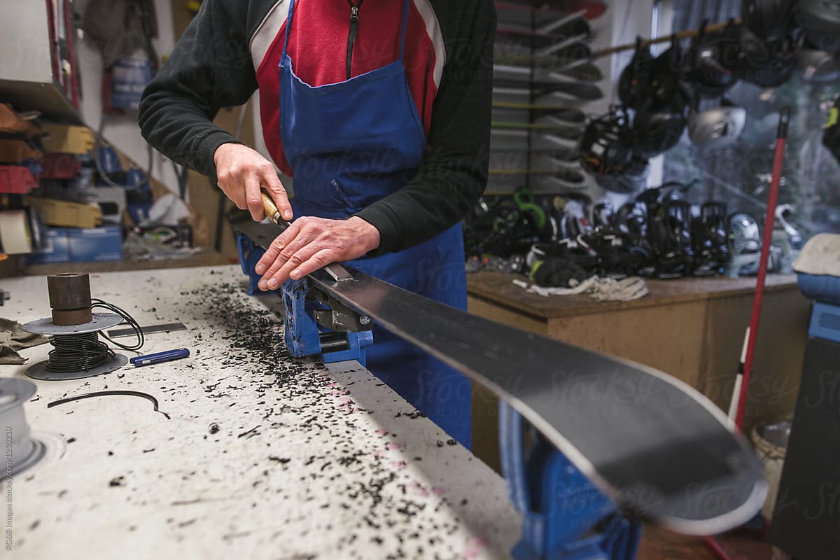 Man fixing a ski using the emery indoor in his workshop