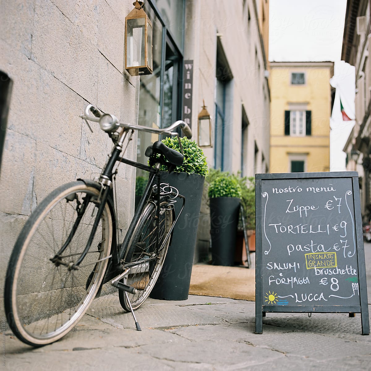 A bicycle leans outside a bistro alongside a chalkboard menu