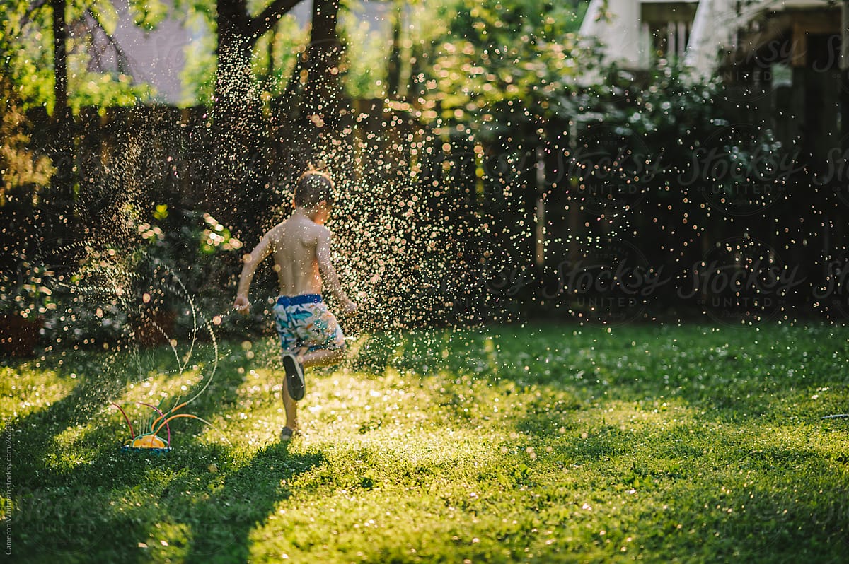 Little boy running through crazy sprinklers