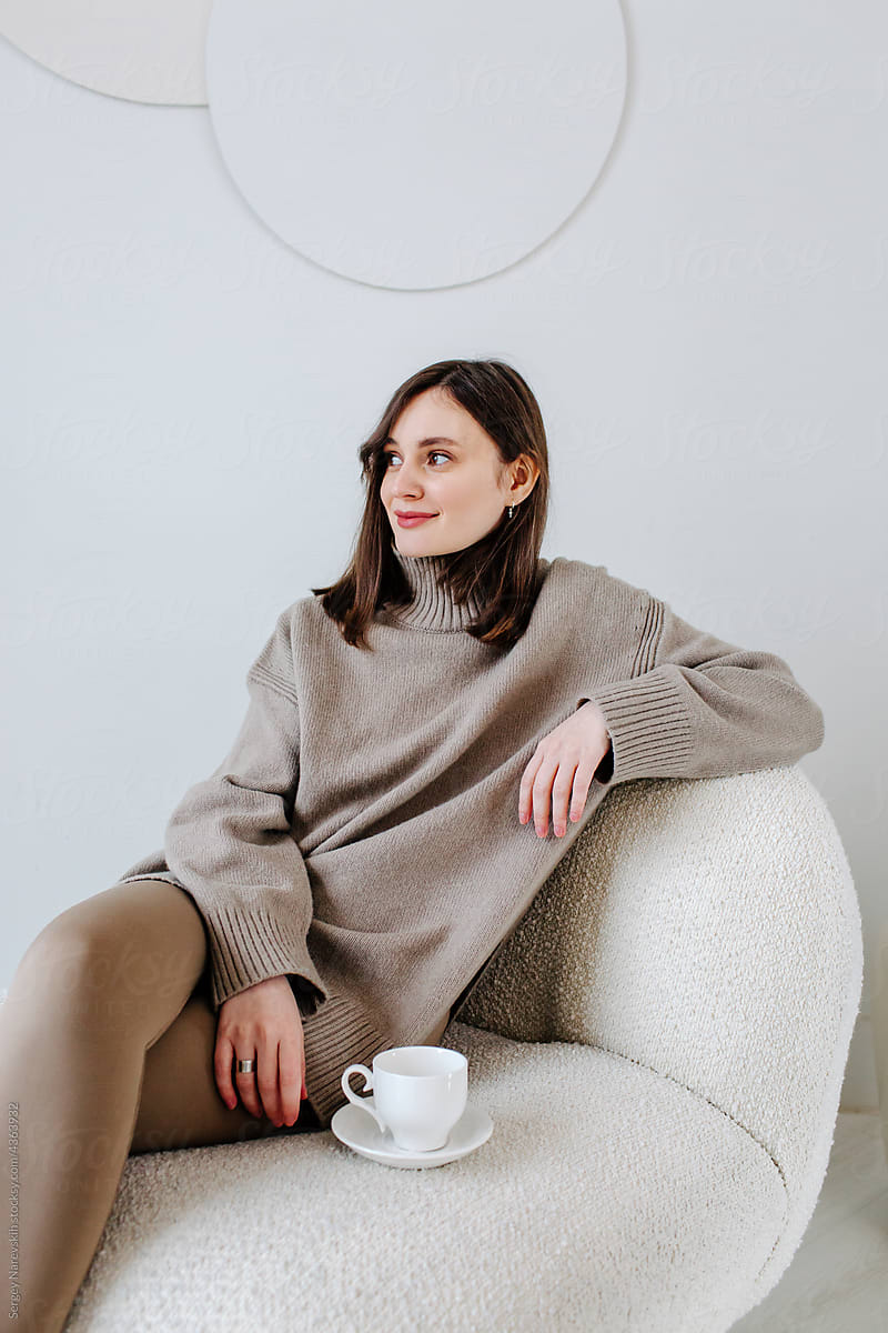 Tender female with cup of coffee in armchair