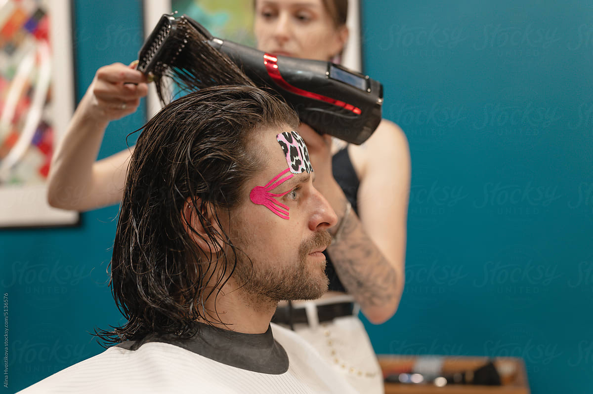 Professional hairstylist drying hair of male client