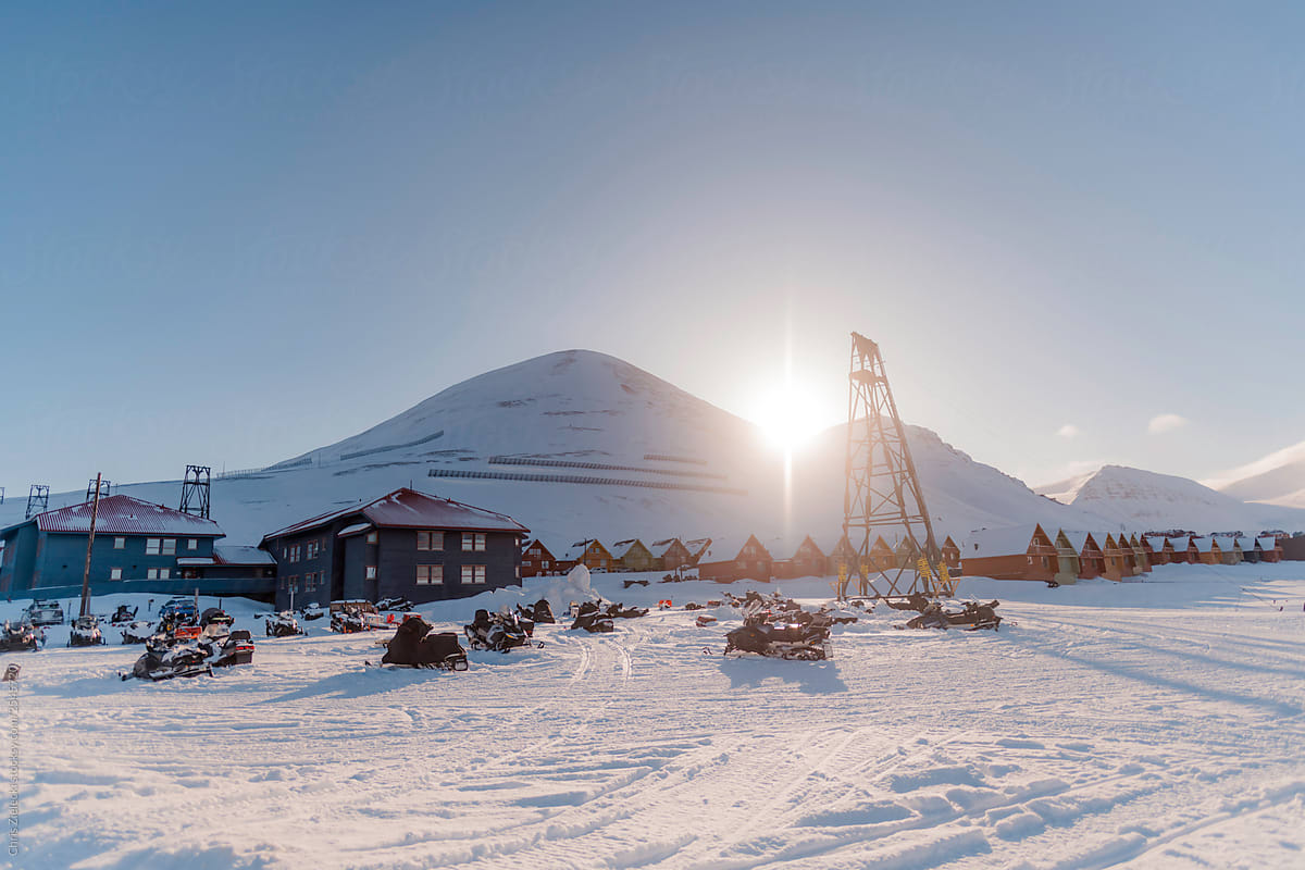 Snowmobiles near houses and mountains in arctic town