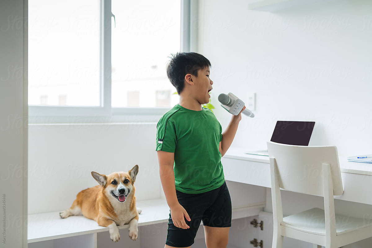 Portrait of asian boy with microphone singing at home