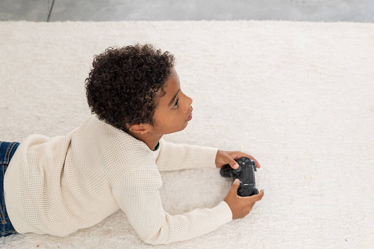 Black boy playing videogame on floor