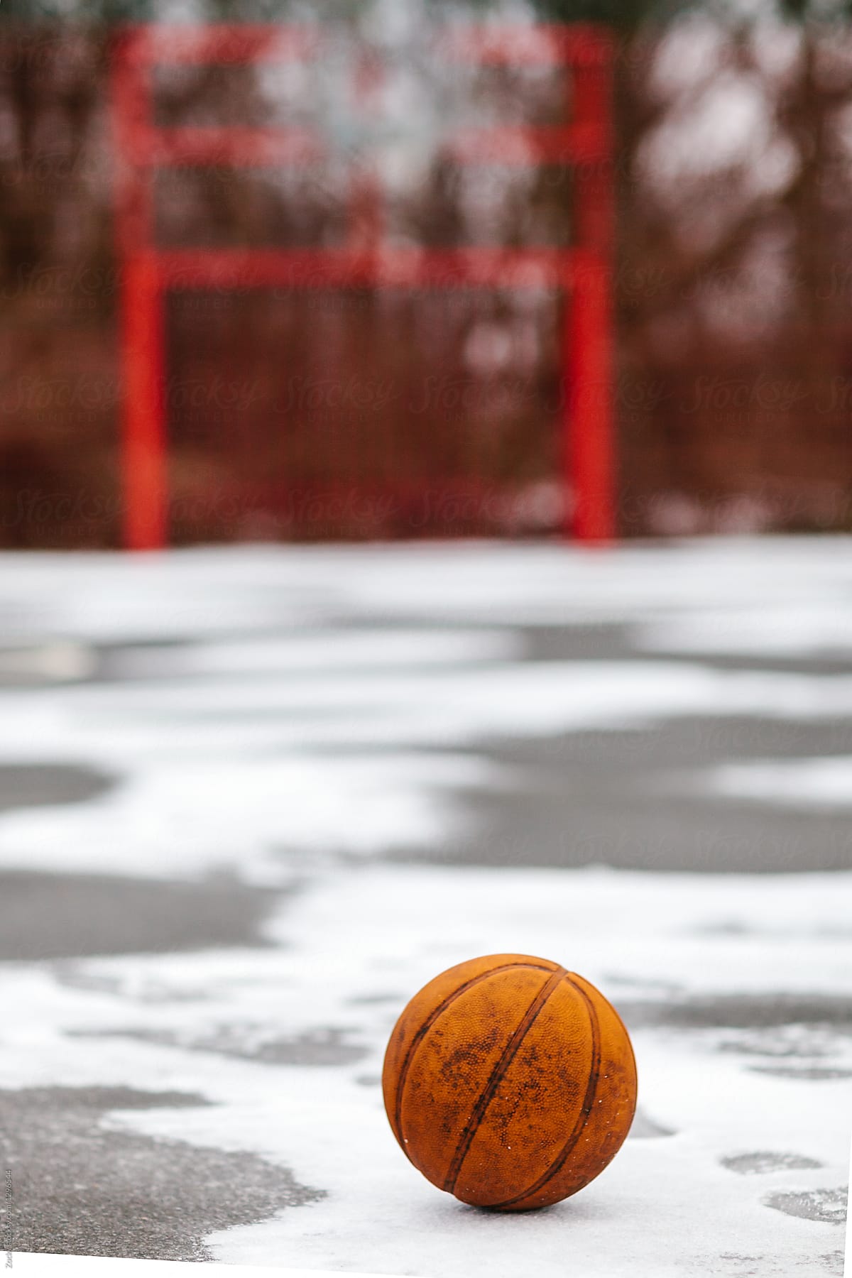 Basketball on a playground covered by snow