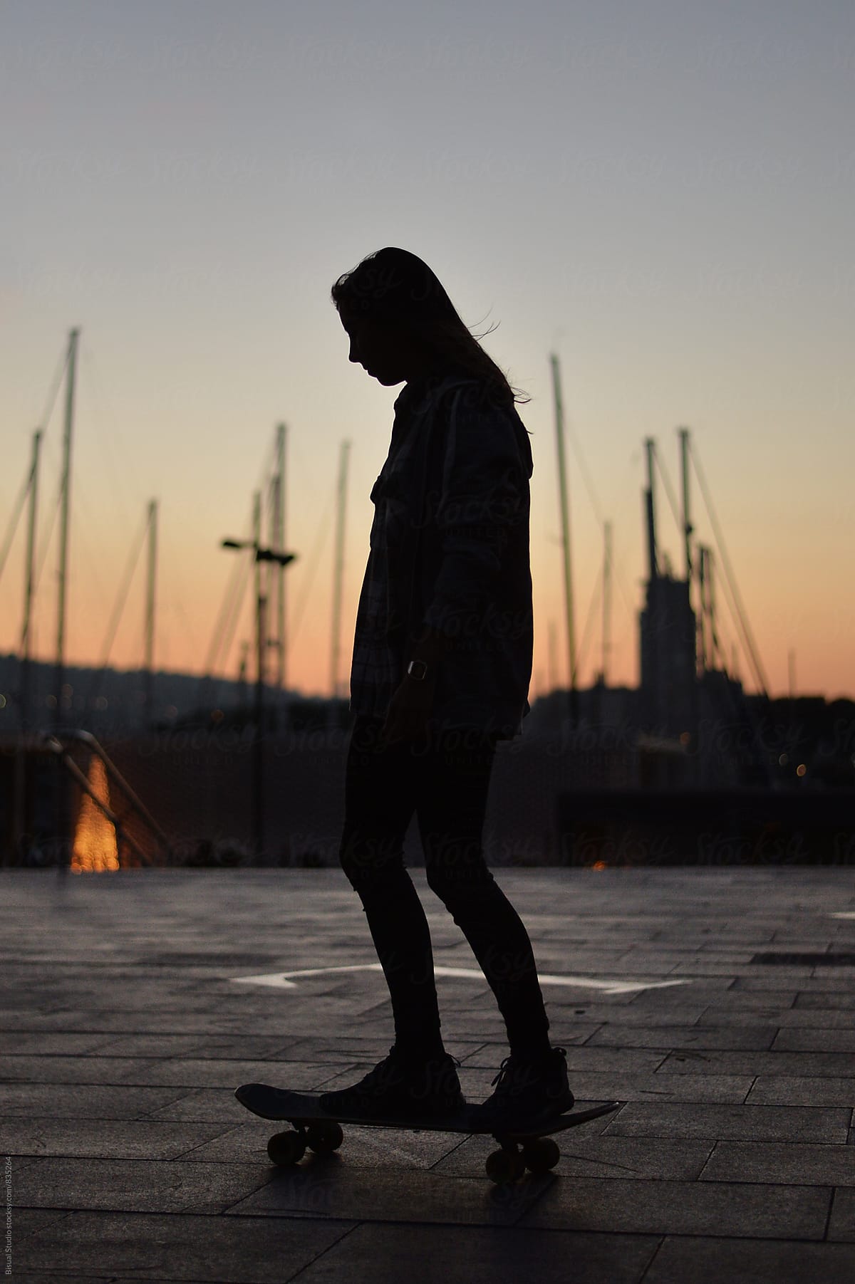 Young woman skating in the port of Barcelona at sunset